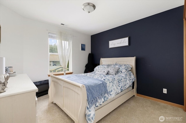 bedroom with baseboards, visible vents, and light carpet