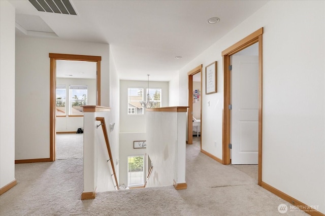 hallway featuring light colored carpet, baseboards, and an upstairs landing