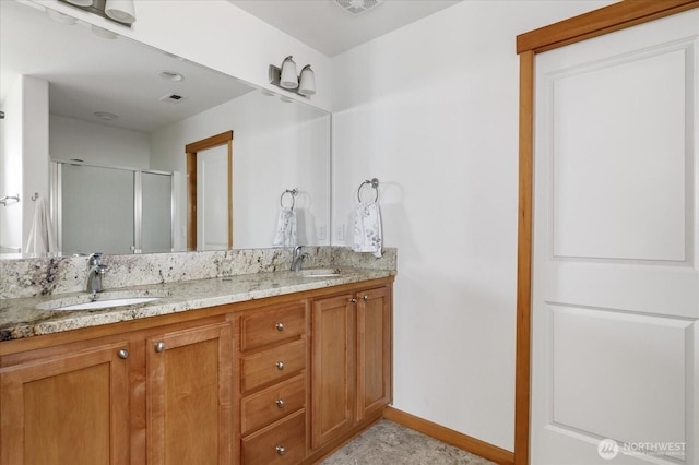 bathroom with double vanity, baseboards, a sink, and a stall shower