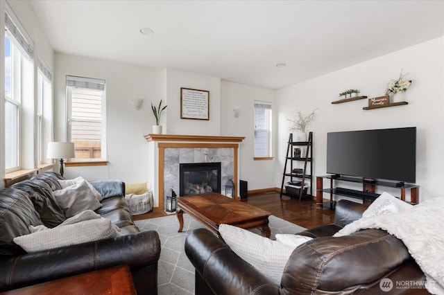 living room with a tiled fireplace, baseboards, and wood finished floors