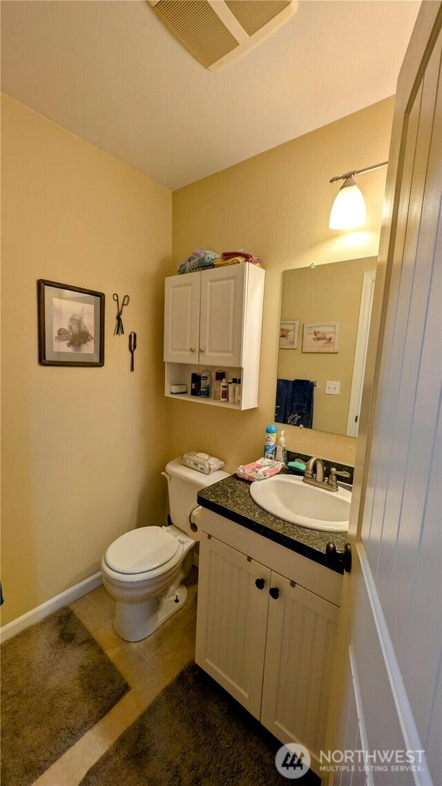 half bathroom with vanity, tile patterned flooring, toilet, and visible vents