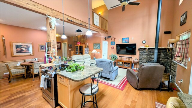 kitchen with electric range, ceiling fan, open floor plan, and a wood stove