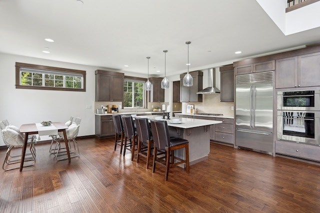 14835 NE 11th Pl, Bellevue, WA 98007 - kitchen with appliances with stainless steel finishes, wall chimney range hood, a kitchen breakfast bar, light countertops, and an island with sink