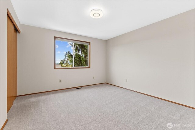 empty room featuring light carpet and baseboards