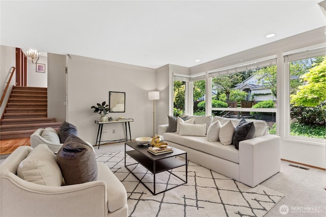 living room with plenty of natural light, stairway, ornamental molding, baseboards, and a chandelier