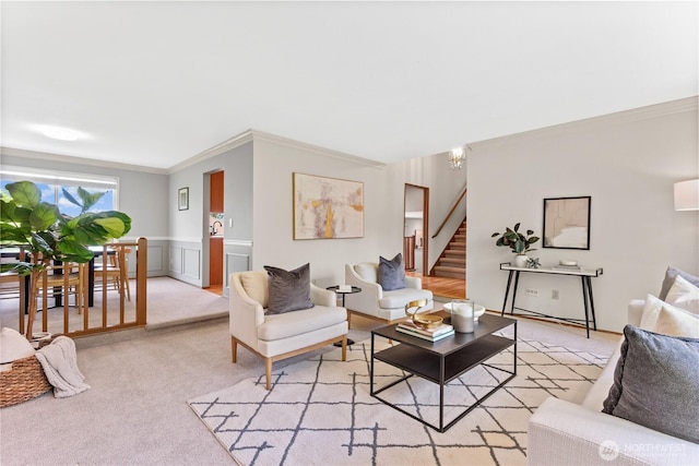 living area featuring crown molding, stairs, a wainscoted wall, a chandelier, and light colored carpet