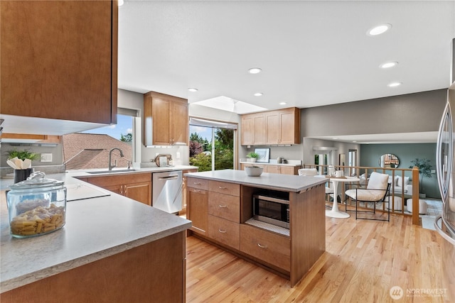 kitchen with stainless steel appliances, a sink, light wood-style floors, light countertops, and recessed lighting
