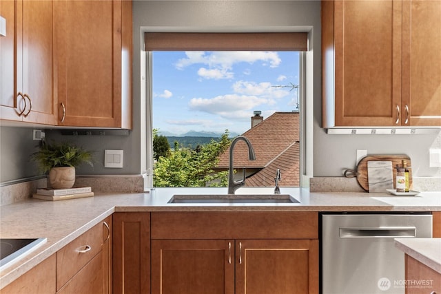 kitchen featuring stainless steel dishwasher, a sink, light countertops, a mountain view, and healthy amount of natural light
