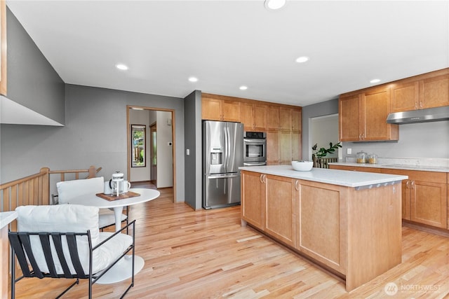kitchen featuring stainless steel appliances, under cabinet range hood, light wood-style floors, light countertops, and a center island