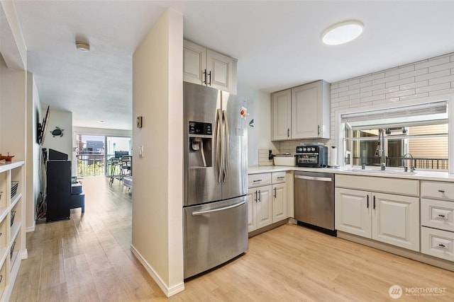 6910 California Ave SW Unit 26, Seattle, WA 98136 - kitchen featuring a sink, stainless steel appliances, backsplash, light countertops, and light wood-style floors