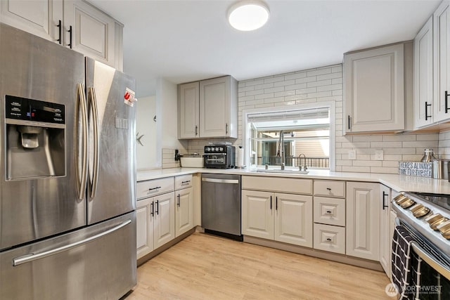6910 California Ave SW Unit 26, Seattle, WA 98136 - kitchen featuring light wood finished floors, backsplash, light countertops, and appliances with stainless steel finishes