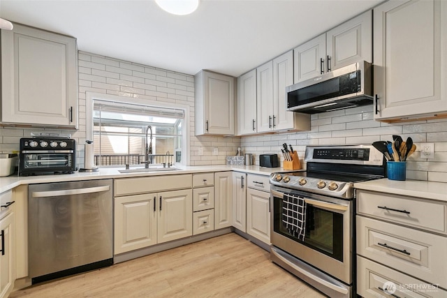6910 California Ave SW Unit 26, Seattle, WA 98136 - kitchen with backsplash, light countertops, stainless steel appliances, and a sink