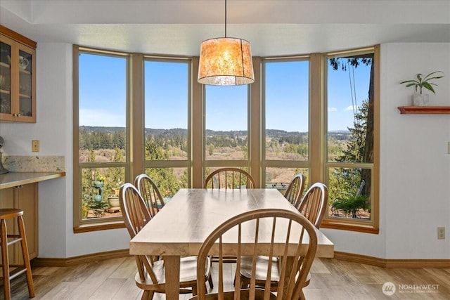 dining area with baseboards and light wood finished floors