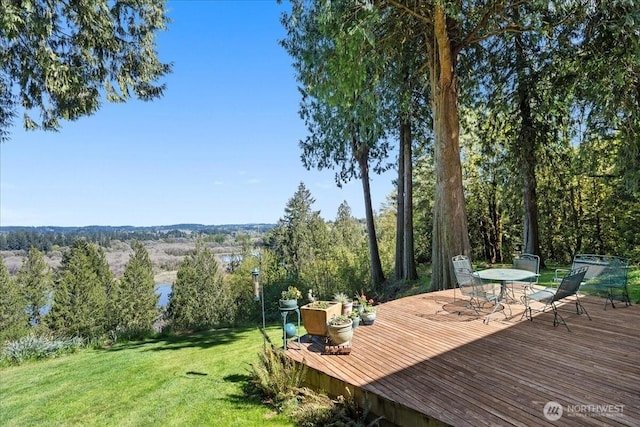wooden terrace featuring a lawn and outdoor dining area