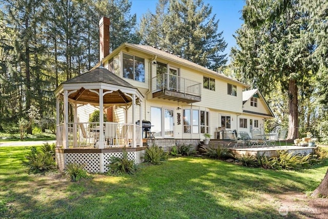back of house featuring a yard, a gazebo, a chimney, and a balcony