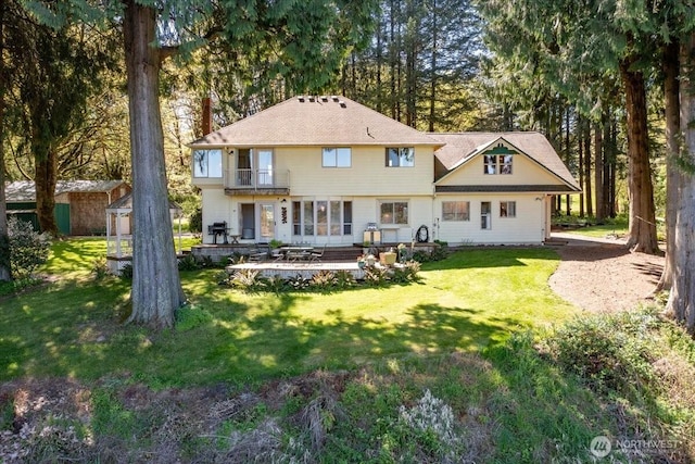 back of property with a yard and a balcony