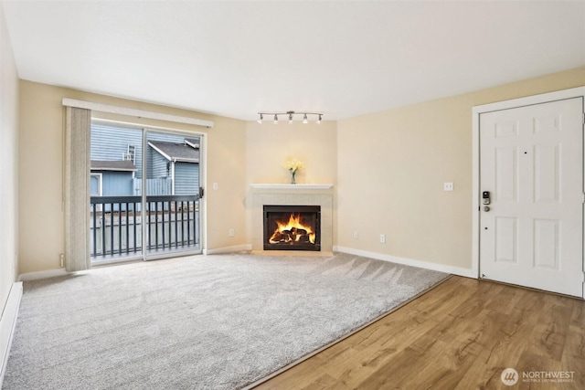 16817 Larch Way Unit B202, Lynnwood, WA 98037 - unfurnished living room featuring a tiled fireplace, baseboards, rail lighting, and wood finished floors
