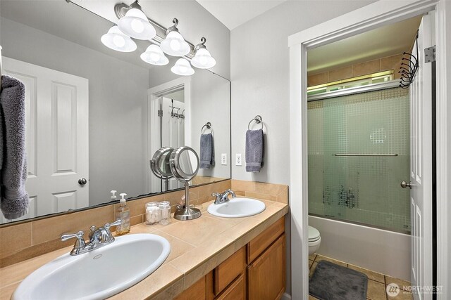 13211 174th St E, Puyallup, WA 98374 - full bath featuring toilet, double vanity, bath / shower combo with glass door, and tile patterned flooring