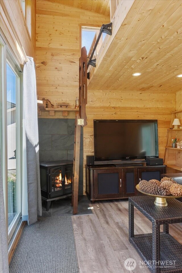 living area with wooden walls, healthy amount of natural light, wood ceiling, and light wood-style flooring