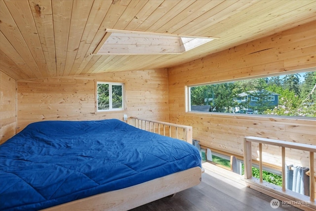 bedroom featuring wooden ceiling, a skylight, wood walls, multiple windows, and wood finished floors