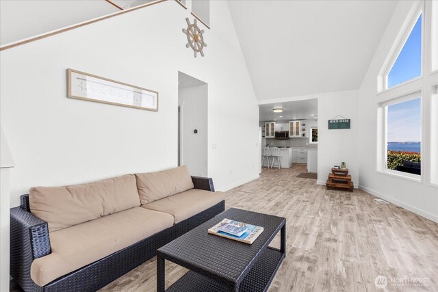 living area with high vaulted ceiling, wood finished floors, and baseboards