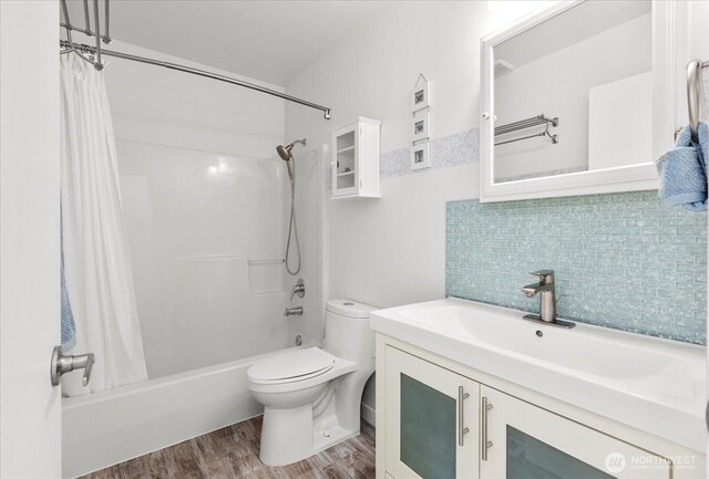full bath featuring wood finished floors, toilet, shower / bath combo, decorative backsplash, and vanity