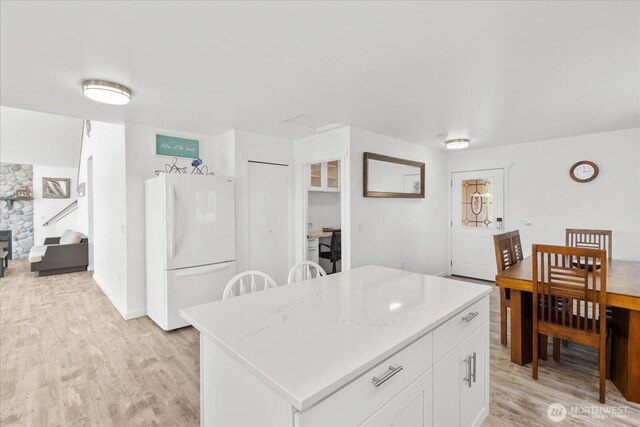 kitchen featuring freestanding refrigerator, light wood-style floors, white cabinetry, and a center island