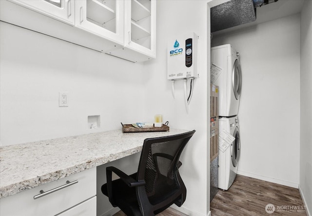 office area with stacked washer and clothes dryer, dark wood-style floors, built in study area, and baseboards