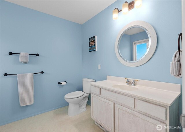 bathroom featuring toilet, vanity, and baseboards