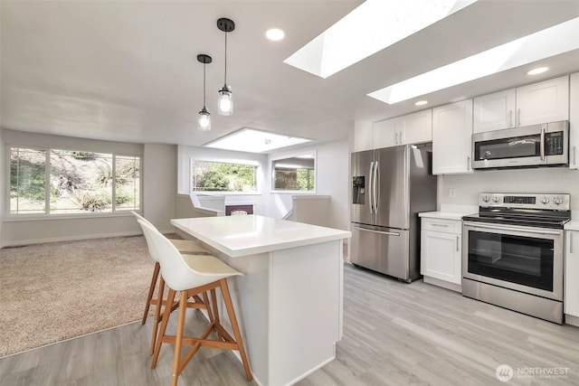 kitchen featuring light countertops, white cabinetry, appliances with stainless steel finishes, and a skylight
