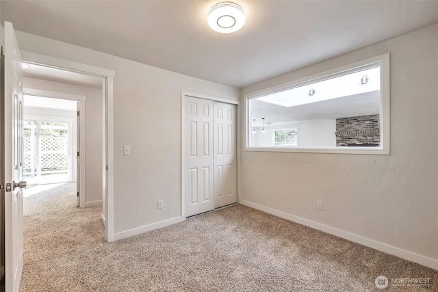 unfurnished bedroom featuring carpet floors, baseboards, and a closet