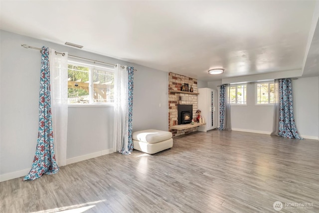 living room with baseboards, visible vents, wood finished floors, and a fireplace