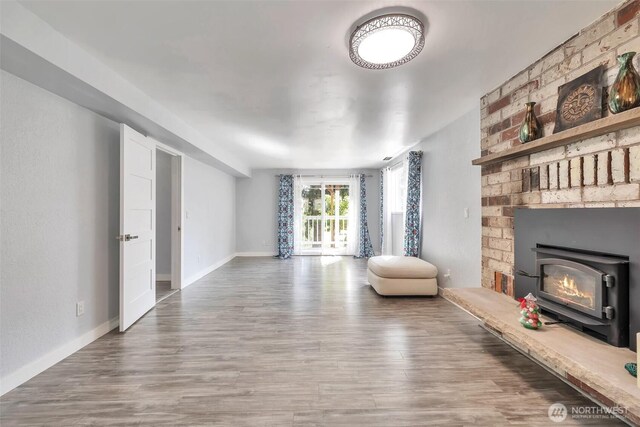 living area with baseboards, a brick fireplace, and wood finished floors