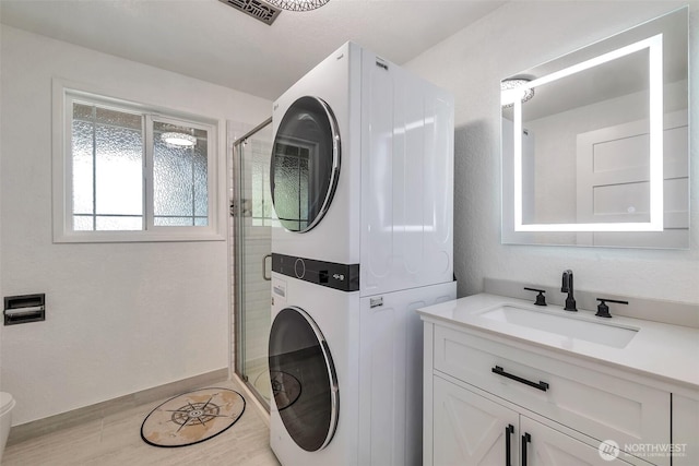 laundry area featuring laundry area, stacked washer and clothes dryer, a sink, and visible vents