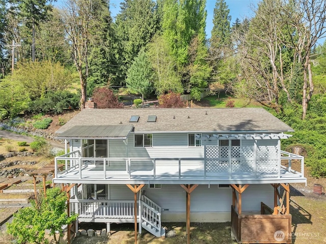 back of house with a shingled roof and a deck