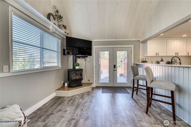 interior space featuring a wood stove, wood finished floors, french doors, and wood ceiling