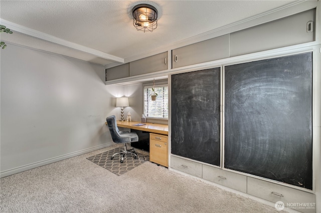 unfurnished office with built in desk, crown molding, carpet flooring, and baseboards