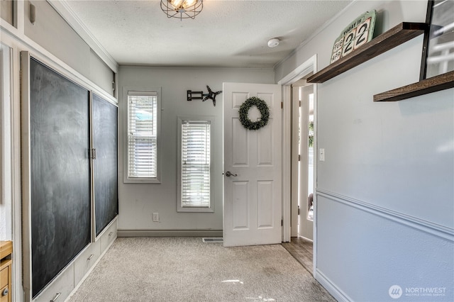 entrance foyer featuring baseboards, ornamental molding, a textured ceiling, and carpet flooring