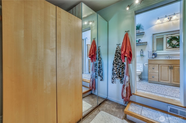 bathroom featuring baseboards, visible vents, toilet, and vanity
