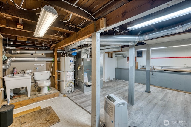 unfinished basement featuring gas water heater, heating unit, and a sink