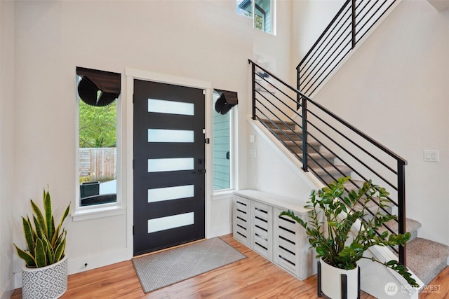 entrance foyer with baseboards, a high ceiling, stairway, and light wood-type flooring