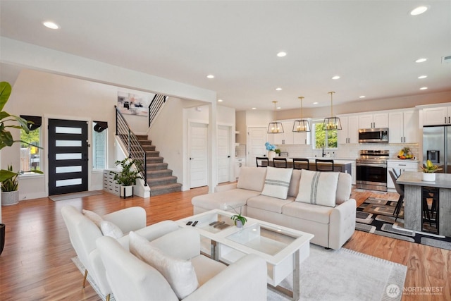 living room with light wood-style floors, recessed lighting, and stairs