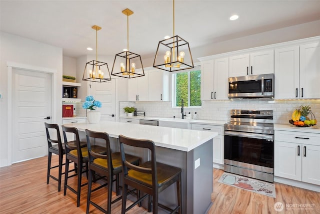 kitchen with a center island, a sink, light countertops, a chandelier, and stainless steel appliances