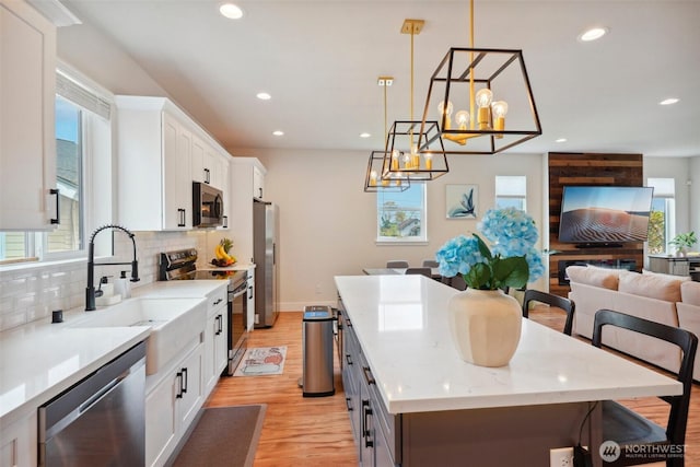 kitchen featuring appliances with stainless steel finishes, a sink, a chandelier, a center island, and open floor plan
