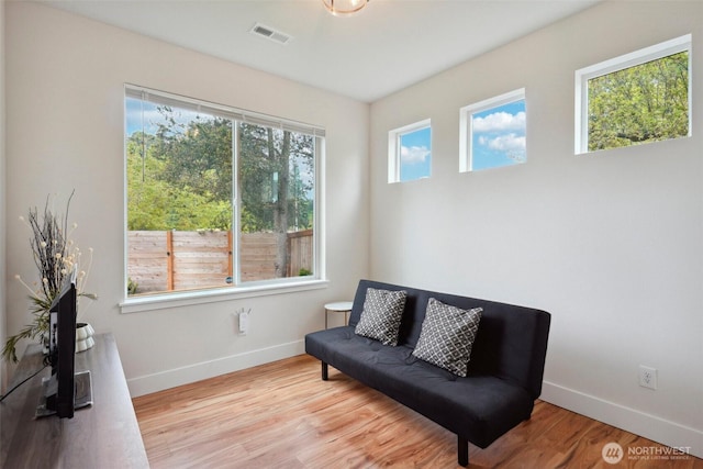 living area with baseboards, wood finished floors, and visible vents