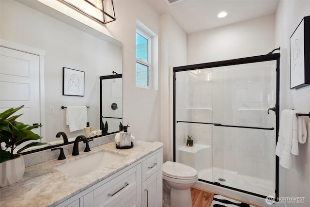 full bathroom featuring vanity, wood finished floors, toilet, and a shower stall