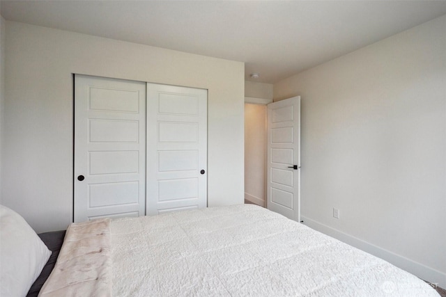 carpeted bedroom with baseboards and a closet