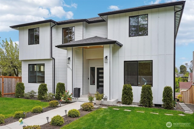 view of front of property featuring board and batten siding, fence, and a front lawn