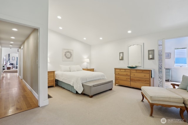 bedroom featuring recessed lighting, arched walkways, light colored carpet, and baseboards