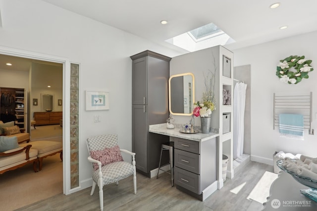 full bathroom with a skylight, wood finished floors, a shower with curtain, recessed lighting, and baseboards